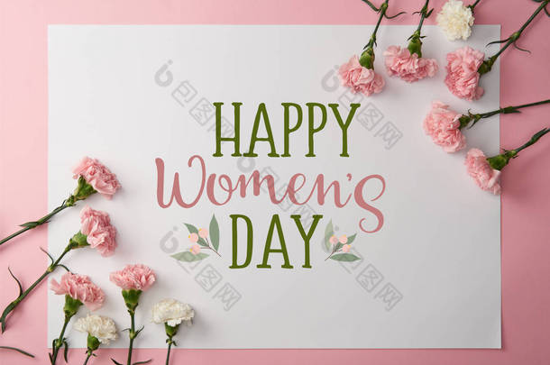 top view of pink and white carnation flowers and greeting card with <strong>happy</strong> womens day lettering on pi