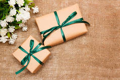 礼品的顶部视图在牛皮纸与绿色缎带与白色的花躺在麻布上.