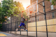 Afro-american basketball player training on a court in New York - Sportive man playing basket outdoo