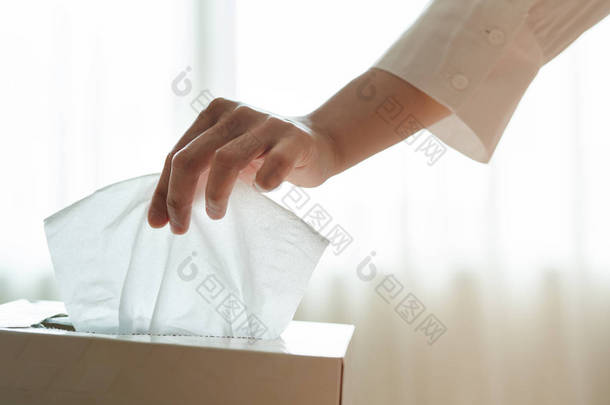 妇女用手从纸盒中挑选餐巾纸/纸巾