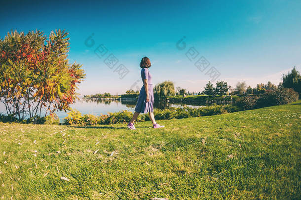 瘦小的女孩走在<strong>河边</strong>。一个穿着衣服的女人在绿草上散步。褐发女郎在<strong>公园</strong>里休息.