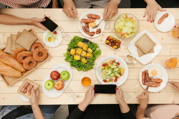 享受与朋友共进晚餐。顶视图的一群人在一起时坐在木桌吃饭
