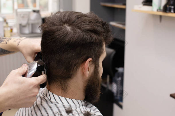 时尚的理发师在理发店理发。胡子男子在沙龙理发.