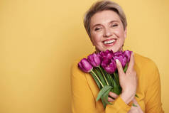 幸福迷人的女人的肖像与紫色郁金香花束在怀里