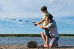 爸爸教儿子在河岸上钓鱼