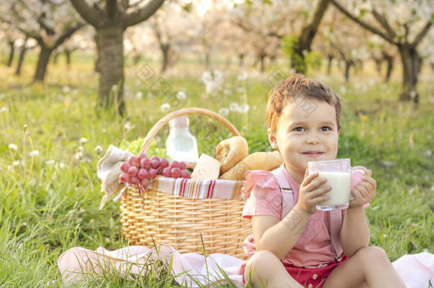 快乐的孩子喝牛奶。在盛开的花朵中野餐。<strong>生日快乐</strong>！人，假期和家庭概念 - 快乐的孩子