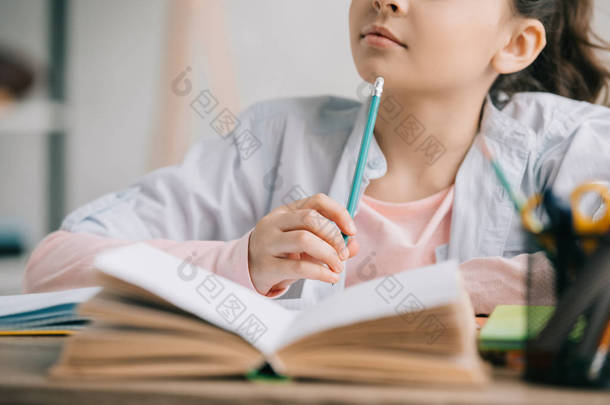 坐在书桌旁看书和<strong>做作业</strong>时，学生拿着铅笔的部分视图