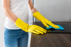 一位来自一家专业清洁公司的年轻女士在家里打扫房间。一个戴黄色手套的男人用清洁用品洗厨房.