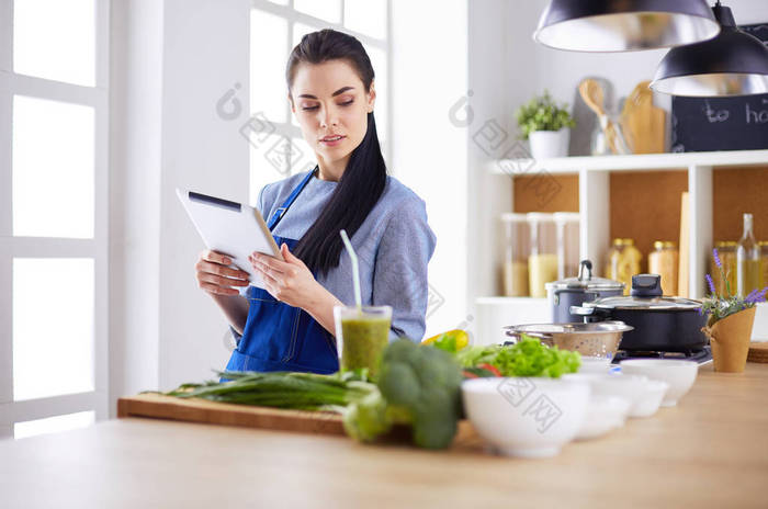 年轻女人在厨房里用平板电脑做饭