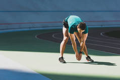 混合比赛运动员在体育场伸展,站在阳光绿地板上 