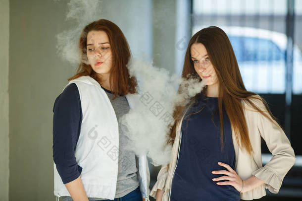 流浪的青少年。夏天，两个穿着休闲装的可爱女孩在户外抽烟。<strong>有害健康</strong>的坏习惯。血管活动.