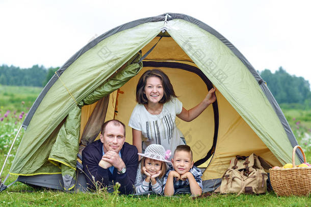 家庭父母和两个孩子住在帐篷里。暑假快乐的母亲、父亲、儿子和女儿