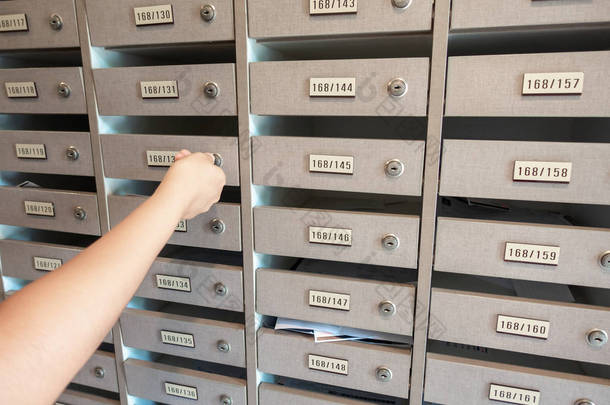 特写的妇女手插入一个钥匙解锁邮箱在公寓, 内部信箱柜在公寓.