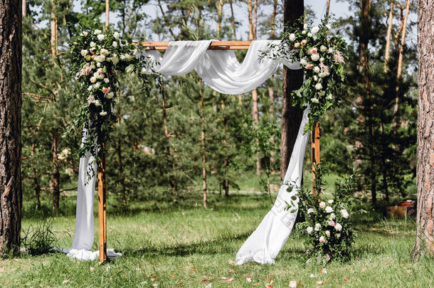 <strong>婚礼</strong>拱门的盛开装饰与玫瑰，康乃馨和紫杉树。美丽的<strong>户外婚礼</strong>。白色和粉红色。<strong>婚礼</strong>照片区。花卉概念。<strong>婚礼</strong>详情