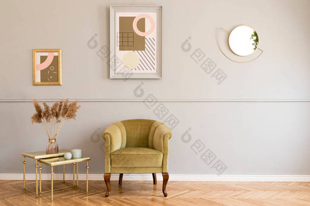 时尚和豪华的客厅的公寓内部与优雅的绿色扶手椅，<strong>复古</strong>的<strong>桌子</strong>与鲜花和别致的配件。在成型灰墙上模拟绘画框架。最小的家居装饰.