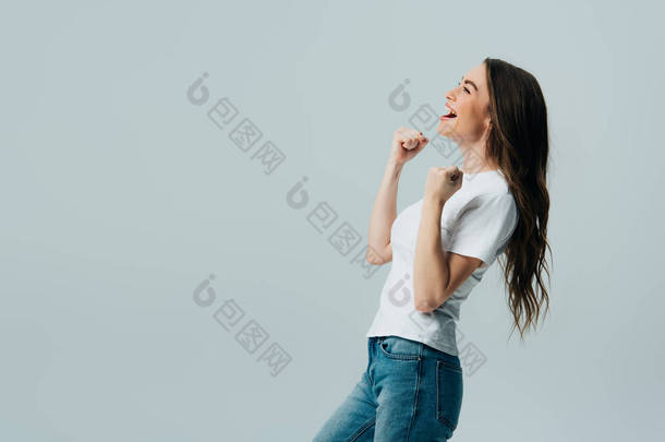 侧视图的快乐美丽的女孩在白色T恤显示是手势孤立在灰色