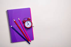 时间管理理念。红色复古闹钟、铅笔和紫色记事本