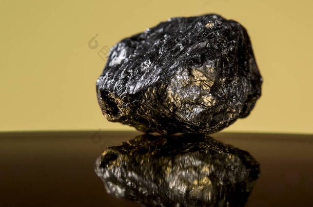 一小块<strong>厚重</strong>的矿物岩石，具有金色特征，在橙色<strong>背景</strong>下闪闪发光