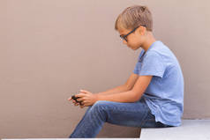 男孩坐在手机和玩网络游戏户外