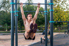 挂在健身站执行腿引发的运动员。交叉培训，培养出 abs 肌肉工作的核心