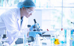 亚洲女科学家、研究员、技术员或学生使用显微镜进行研究或实验,显微镜是医学、化学或生物实验室的科学设备
