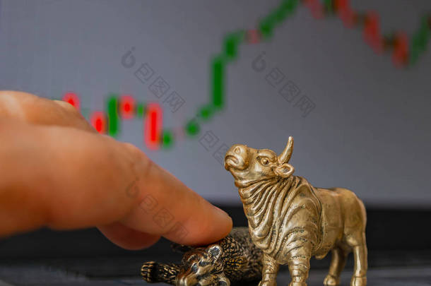 牛市和熊市作为股票交易的象征，在模糊的价格图形背景。商品与金融市场象征意义的概念.