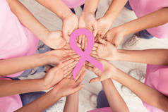 妇女手拿着粉红色的乳腺癌丝带站在一起