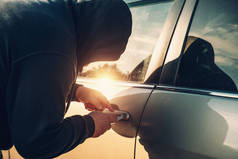 汽车抢劫犯或小偷试图打破汽车门锁，关门。 偷车概念
