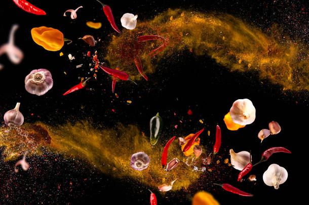滚烫的红辣椒，大蒜，不同的香料粉肉桩在黑色背景上飞舞运动冻结照片组合