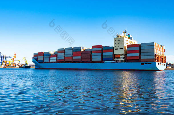 货船离开港口。 在蓝水蓝天背景下的集装箱船. 这艘船装有五颜六色的集装箱. 国际货物运输。 4.海上货物运输。 舰队
