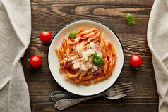 搭配番茄酱和意大利面的意大利面，在配料附近的白盘上，还有木桌上的餐具，尽收眼底