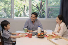 父亲、母亲和儿子笑容满面，快乐快乐地一起在家里的饭厅里作为快乐的家庭主题一起吃早餐和讨论