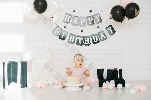 一岁生日的女孩的第一个蛋糕。 生日宴会装饰是黑白相间的. 这孩子尝起来甜甜的. 生日快乐