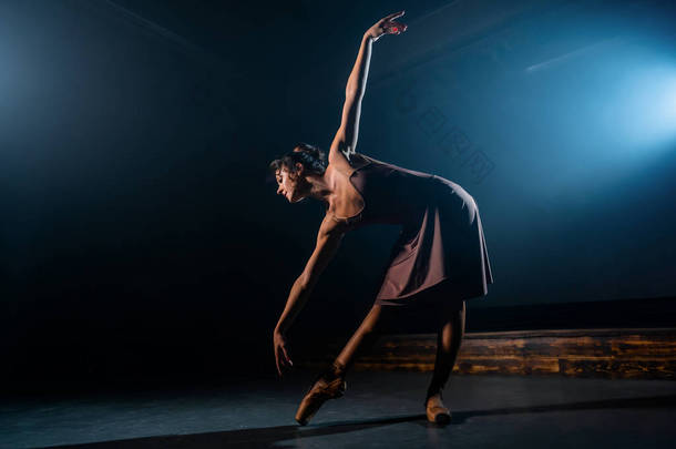 米色优雅的芭蕾舞演员穿着古典或现代芭蕾舞的<strong>舞蹈</strong>元素在黑暗中与泛光灯背光。 黑色<strong>背景</strong>上的烟雾。 艺术概念.