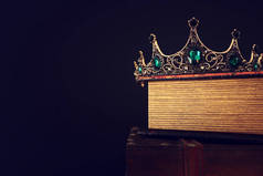 精美的女王/王冠盖在旧书和木制桌子上的低调形象。 老旧的过滤。 幻想中世纪时期