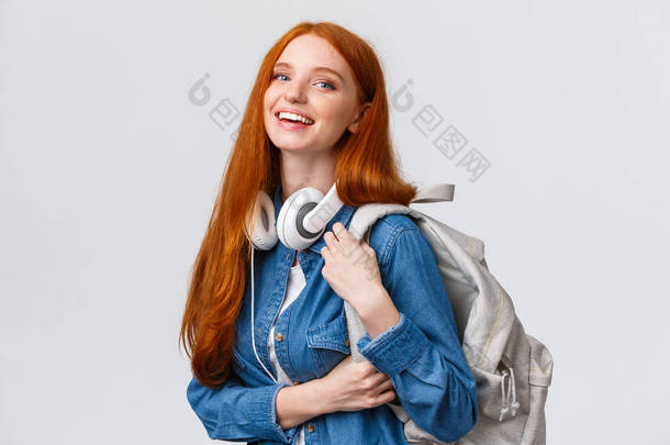 大学生活、现代生活方式和教育观念.红头发、头戴耳机、背包、<strong>笑脸</strong>相机的快乐的红头发女学生