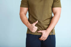 年轻男子，有健康的泌尿生殖系统，在浅色背景下显示大拇指向上