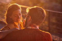 微笑的女孩和她的男人在夕阳西下享受着.
