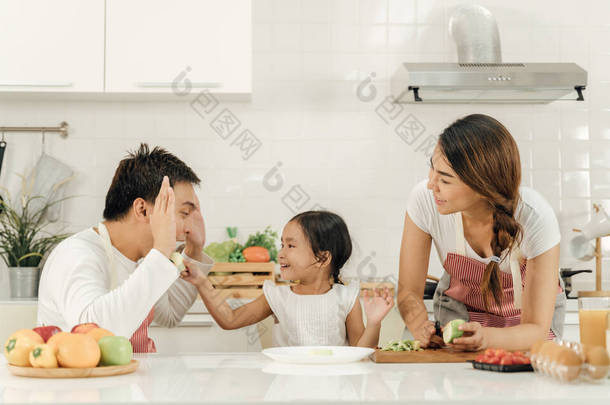 健康的食物在家里,快乐的家庭在厨房概念.母亲和女儿正在吃早饭。<strong>可爱</strong>的小女孩和她<strong>美丽</strong>的父母在厨房做饭时正在做早餐.