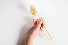 cropped view of woman holding delicious Chinese boiled dumpling with chopsticks on white background