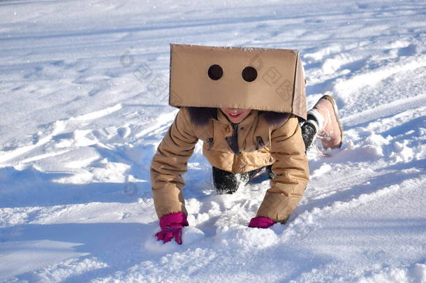 那女孩爬到箱子下面去了.让孩子们享受寒假学校外的冬季活动。雪地上的游戏