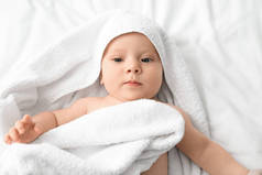 抱着毛巾躺在床上的可爱小宝宝的画像