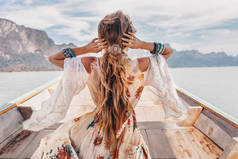 热带探险中穿着连衣裙的美丽的波希米亚女人在船上摆姿势