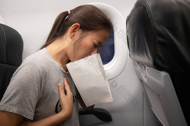 飞机上的女乘客感到晕机，在飞机上使用气喘袋因晕机呕吐而感到恶心