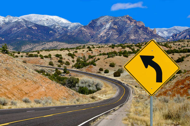 曲线警告标志：在新墨西哥州北部，一个路标<strong>提醒</strong>驾车者<strong>注意</strong>一条弯曲的山路.