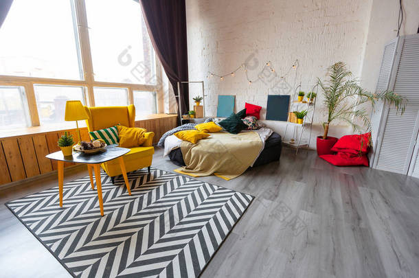 斯堪的纳维亚风格的时髦时尚奢华室内设计- -宽敞宽敞的工作室式公寓，配有明亮的黄色家具，装饰着新年树.