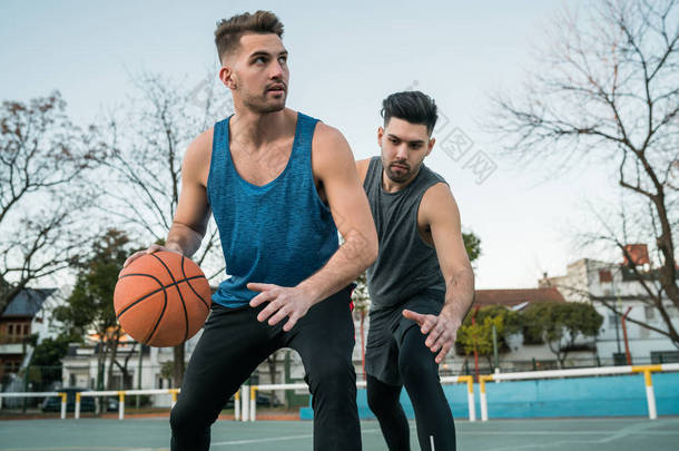 年轻的篮球运动员在室外场地一对一地打球。体育和篮球概念.