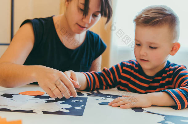 有幼儿的年轻母亲在节假日的家庭时间里为孩子们做手工蜘蛛