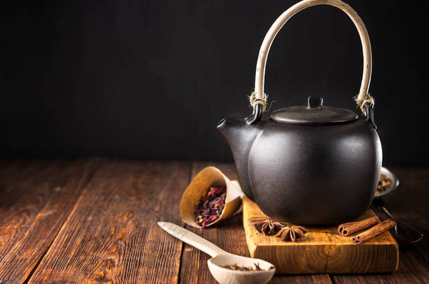 红瓷茶壶，茶，不同的茶和香草，木制背景.