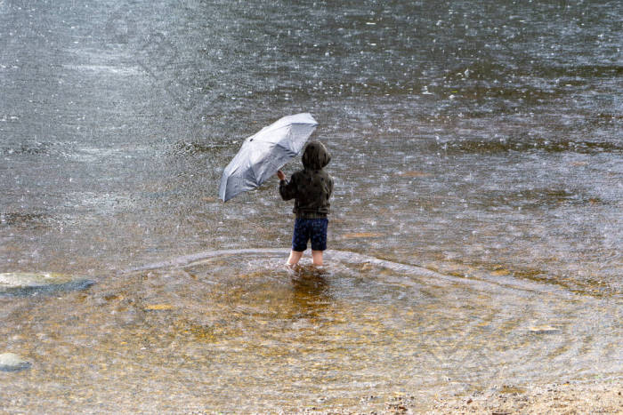 一个男孩拿着雨伞避雨图片-包图网企业站
